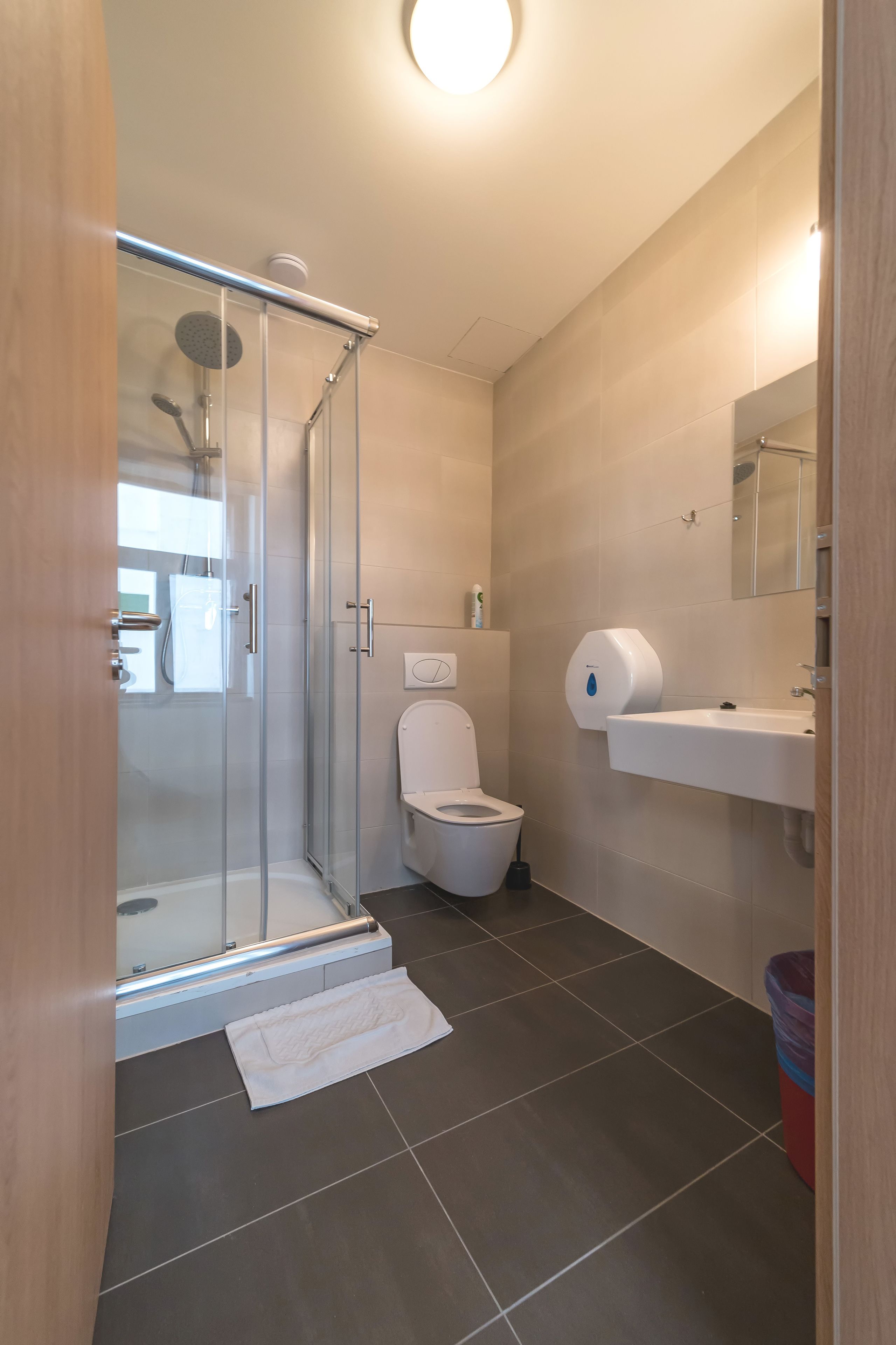 Un baño moderno con cabina de ducha de vidrio, inodoro, lavabo y espejo.