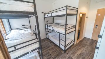 Habitación tipo dormitorio con literas, suelo de madera y una puerta con letrero de prohibido fumar.