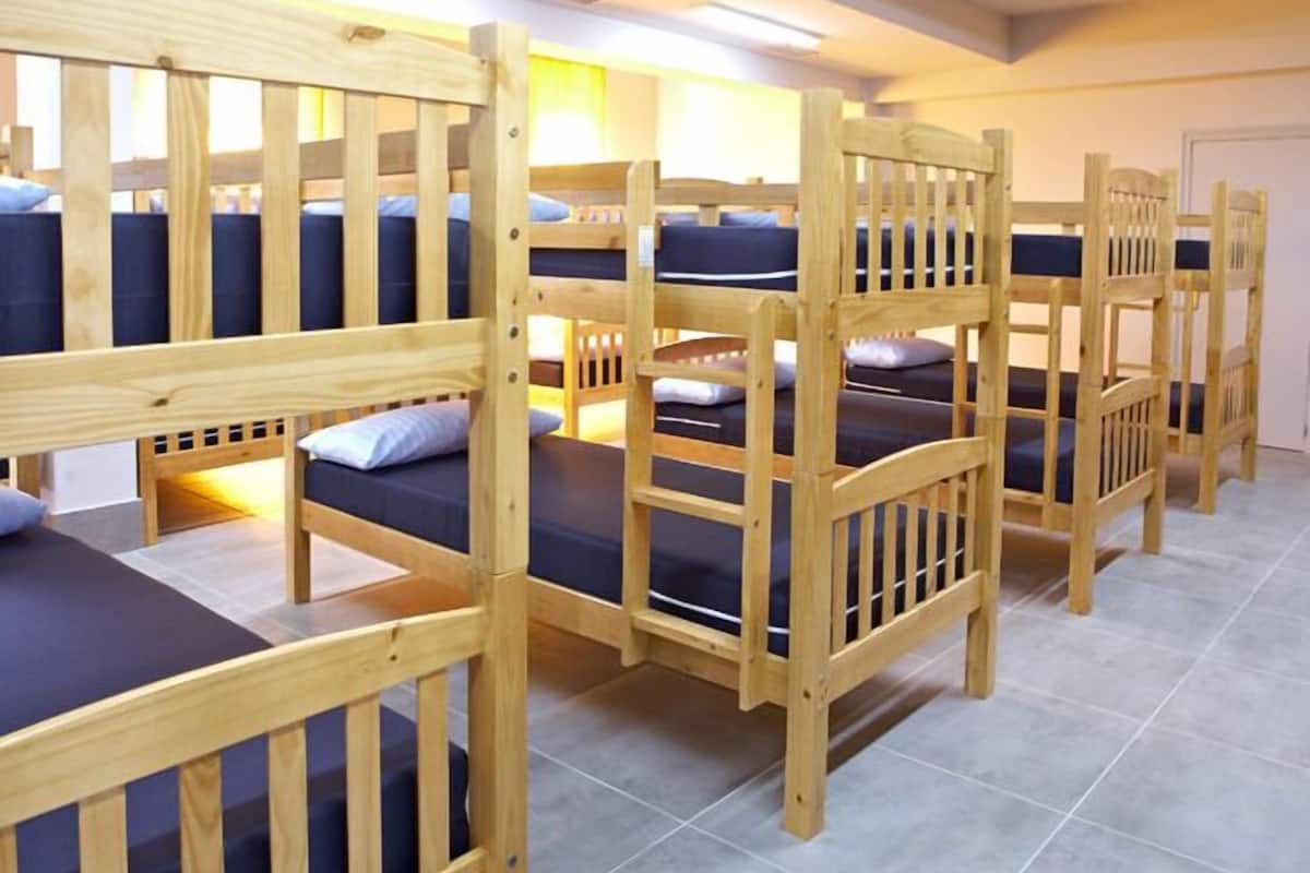 Een studentenkamer met stapelbedden, elk met een kussen en een deken.