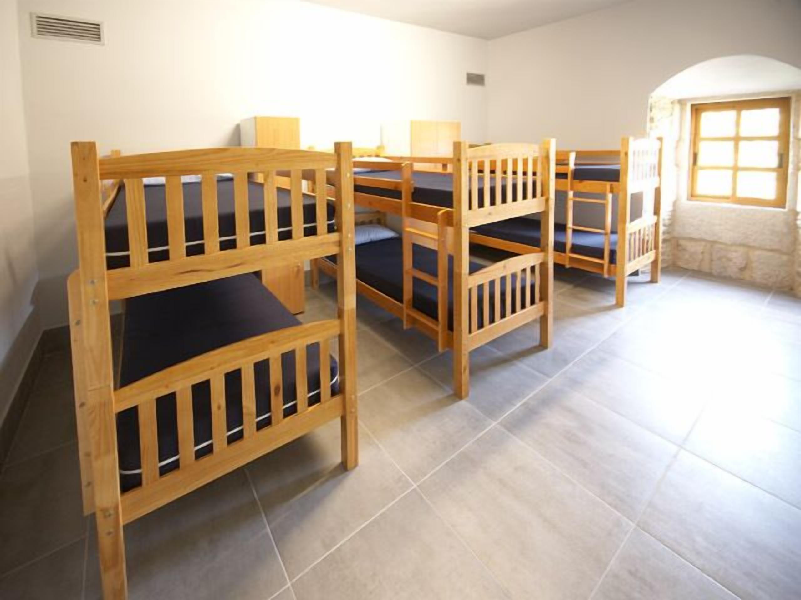 A dormitory room with bunk beds and a small desk.