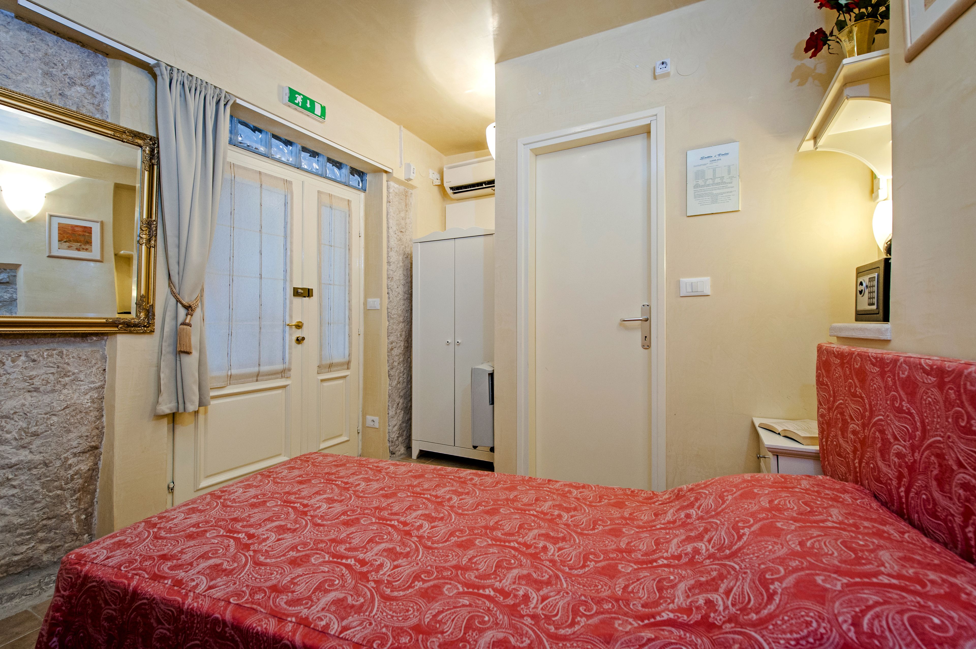 A hotel room with a bed, a bathroom, a wardrobe, and a mirror.