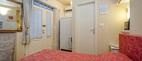 A hotel room with a bed, a bathroom, a wardrobe, and a mirror.
