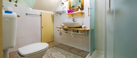 Un baño con inodoro, lavamanos, ducha y espejo.