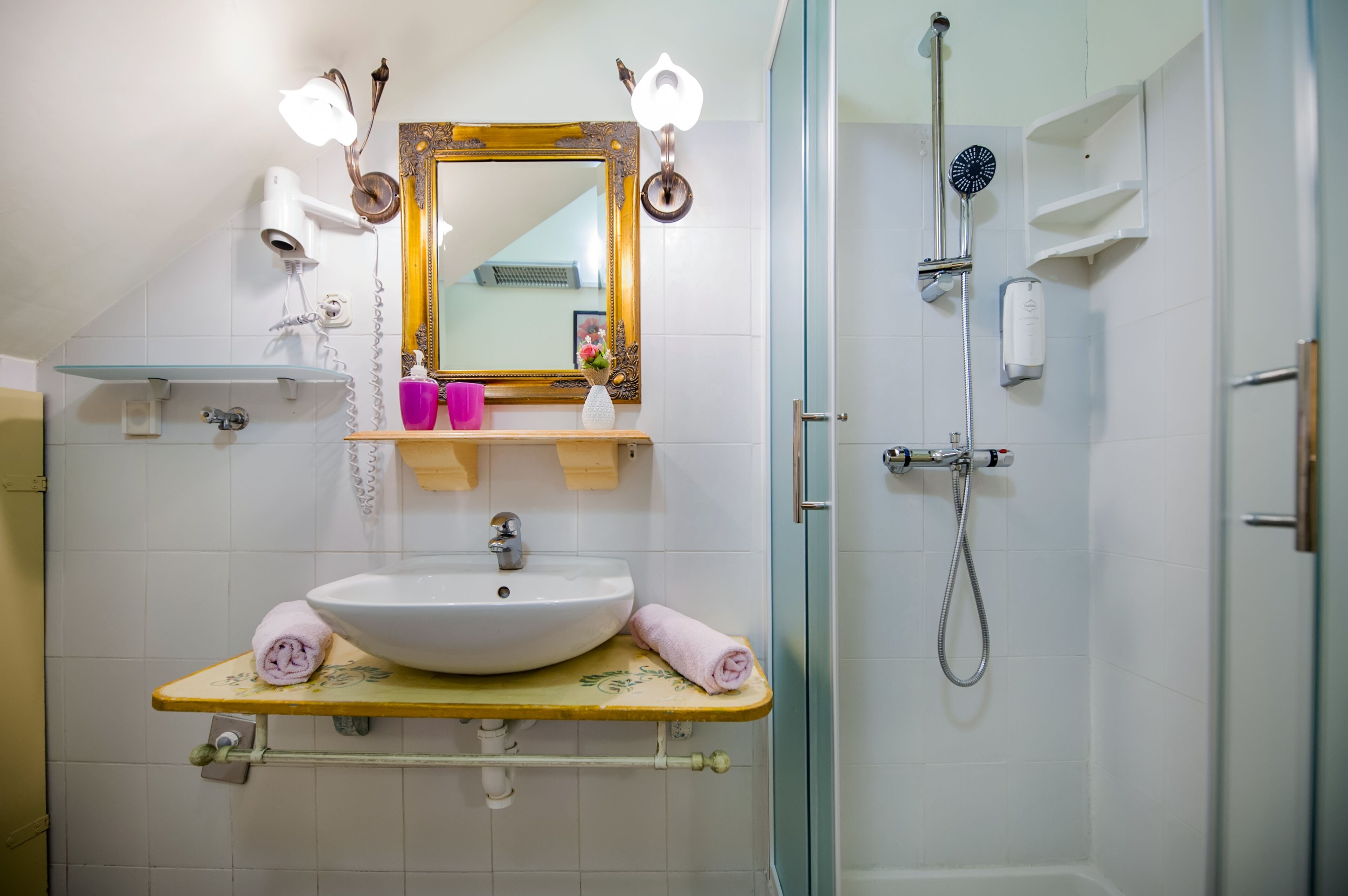 A bathroom with a sink, mirror, towel rack, and shower.