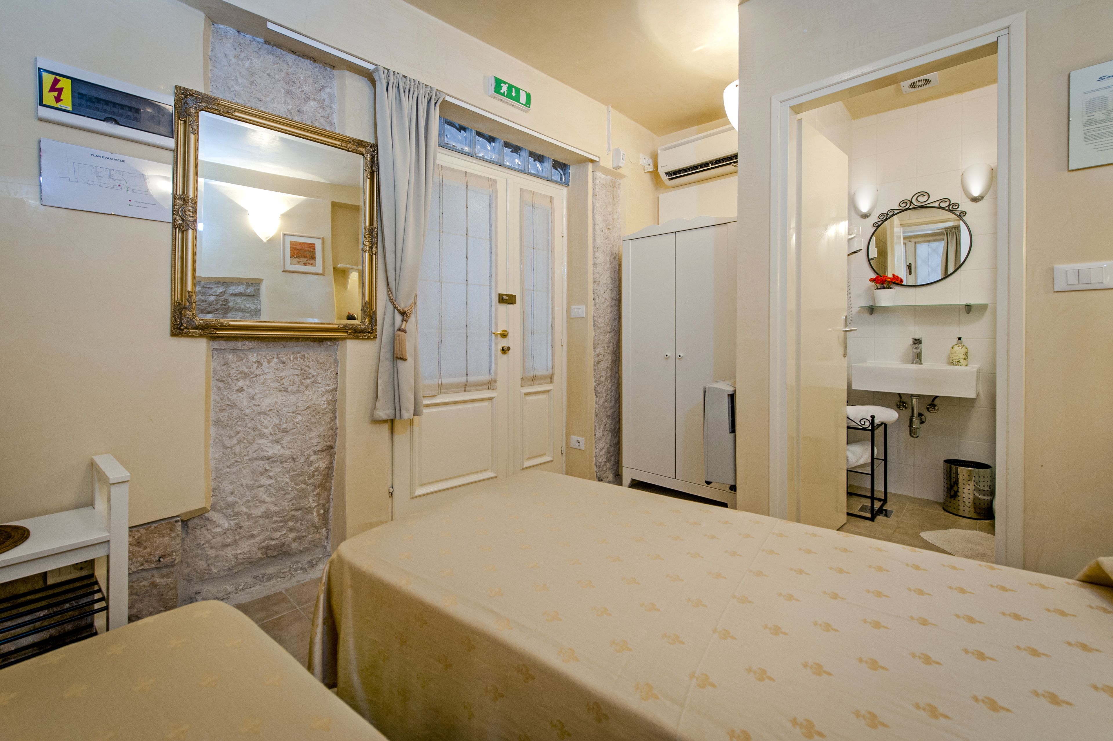 A hotel room with a bed, a wardrobe, a bathroom with a mirror, and a reception area.