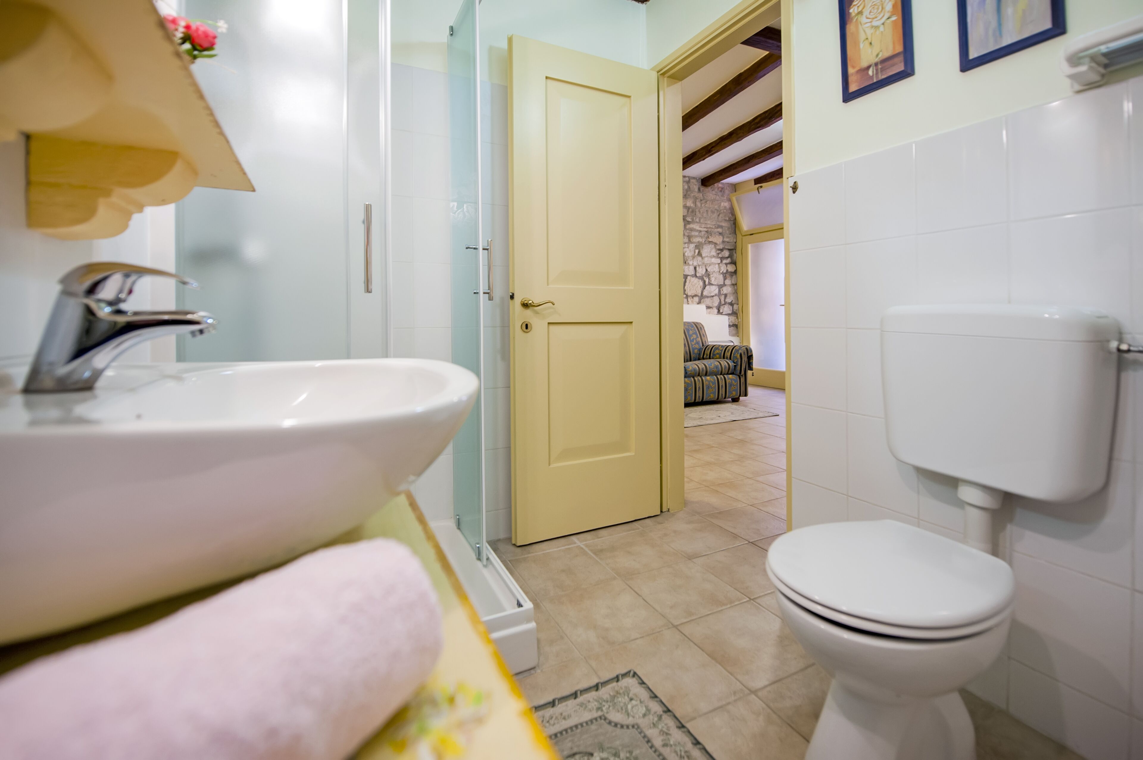 A bathroom with a sink, toilet, and a door leading to a living area.