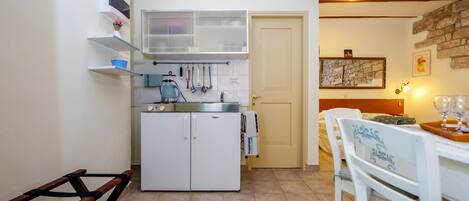 Cocina compacta con refrigerador, un lavamanos y zona de comedor con mesa y sillas.