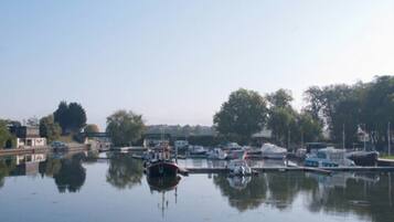 A calm water body with boats docked, surrounded by trees and buildings.