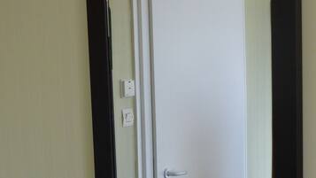 A room with a white door, a light switch, and a power outlet on the wall.