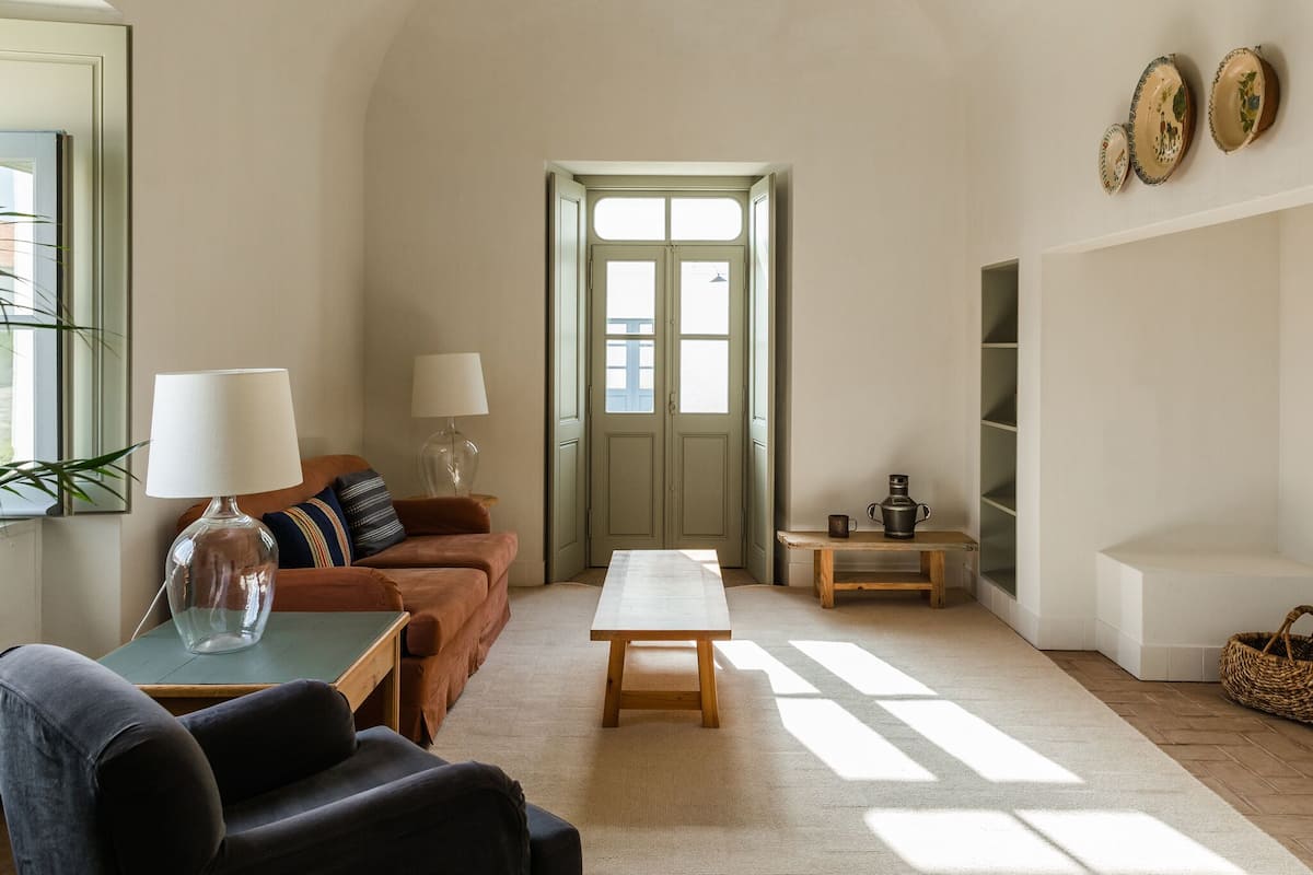 Ein Wohnzimmer mit einer Couch, einem Couchtisch, einer Lampe und einer Tür zu einem anderen Raum.