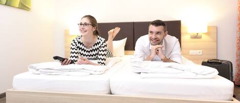 Habitación de hotel con dos camas, una mesita de noche, una lámpara y una maleta.