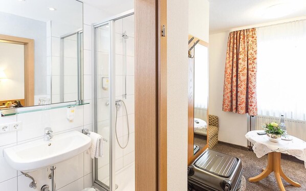 A modern bathroom with a glass shower enclosure, a sink, and a mirror.