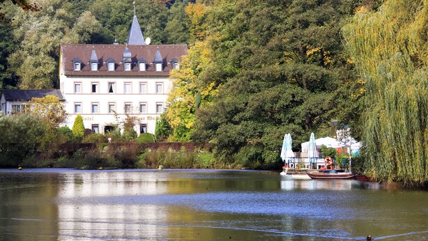 Un hôtel de style architectural européen traditionnel, situé au bord d’une rivière et doté d’un quai pour bateaux.