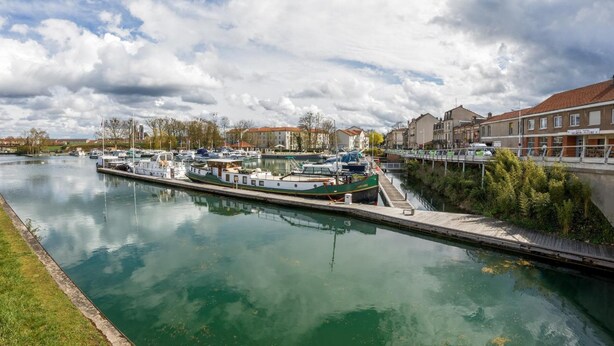 A canal with boats docked, a bridge, and buildings along the water. - ABC Hôtel (Toul)