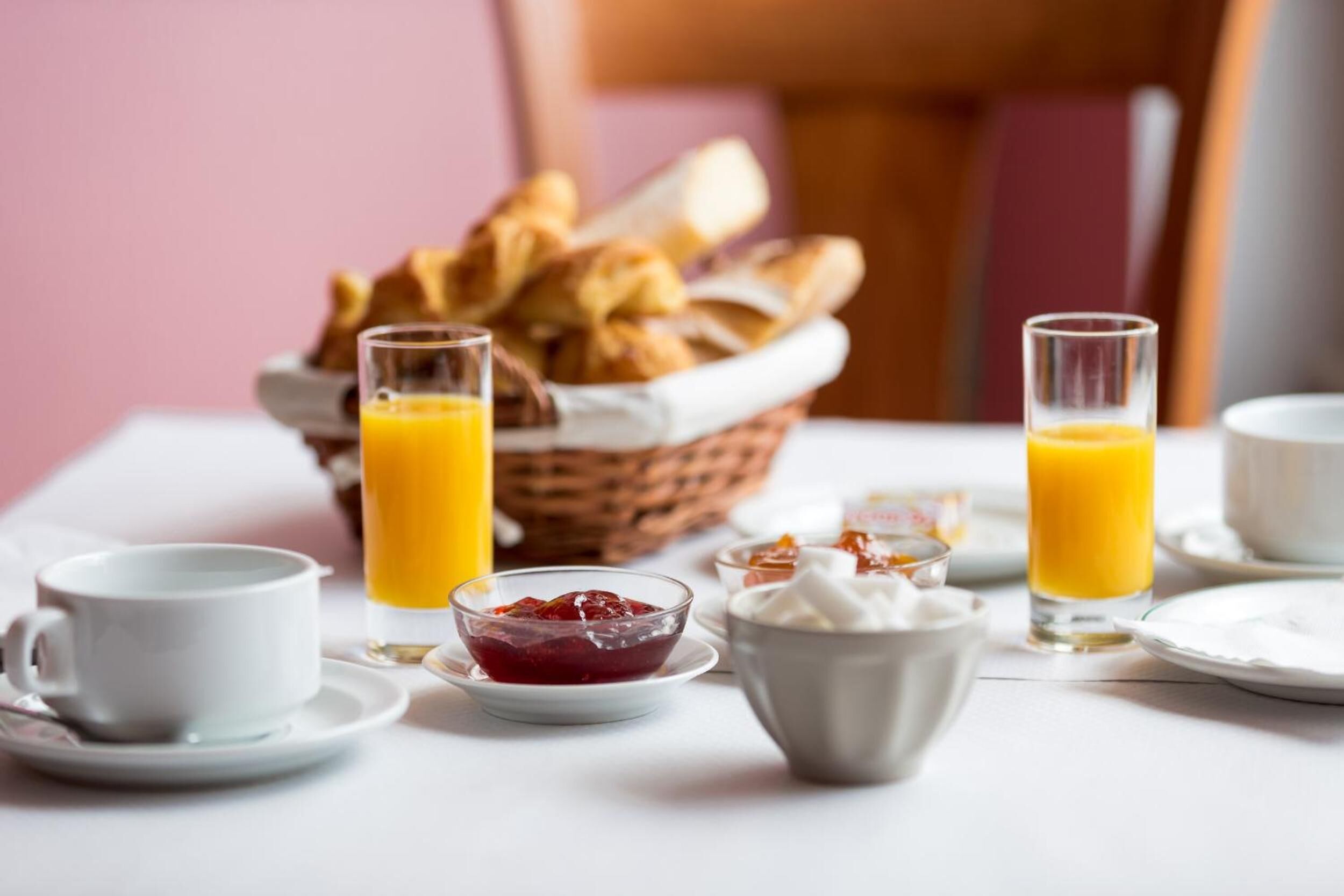 Desayuno con cruasanes, jugo de naranja y un tazón de mermelada.