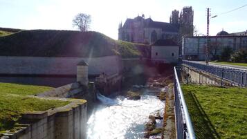 A river flowing through a stone bridge with a historic building in the background.