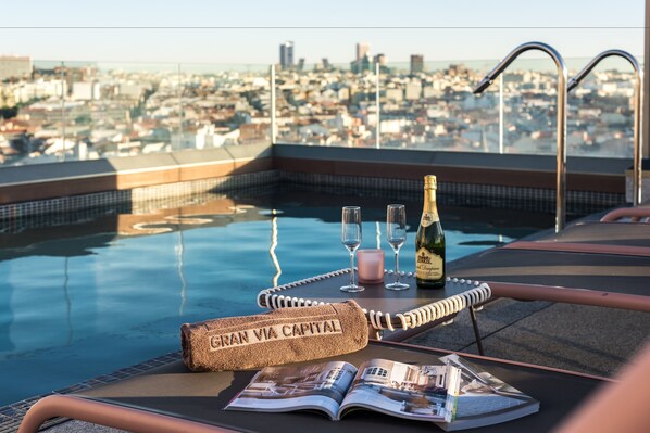 Een seizoensgebonden buitenzwembad en ligstoelen