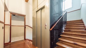 A wooden staircase with a metal railing, leading to an elevator. - Smartr Madrid Chueca  (Madrid)