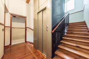 Eine Holztreppe mit Metallgeländer, die zu einem Aufzug führt.