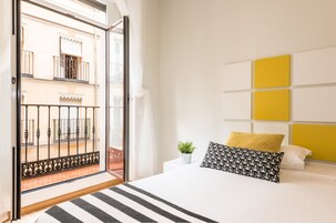Ein Schlafzimmer mit einem Bett, Balkonblick und einer gelben Akzentwand.