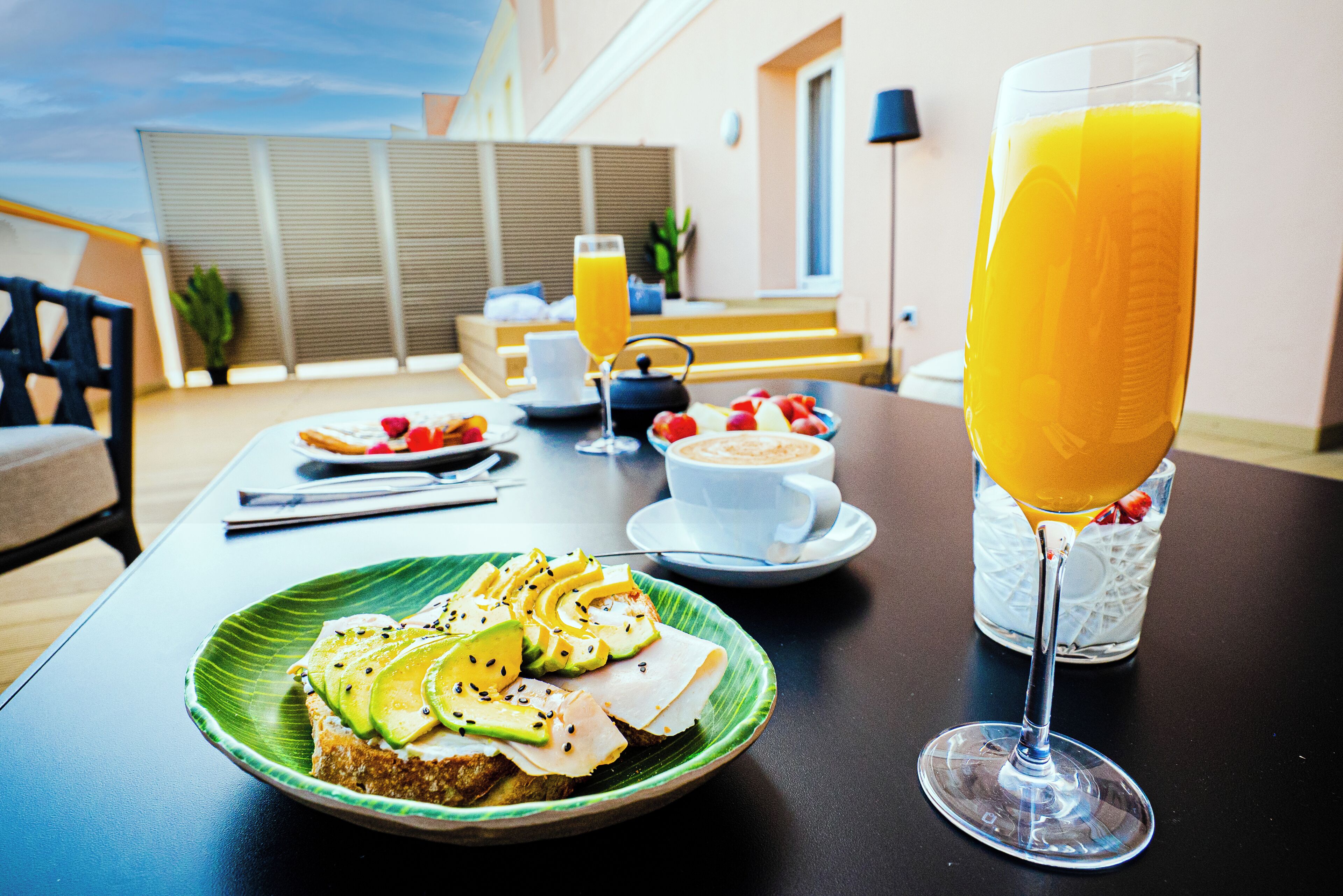 A breakfast setting with toast, fruit, and a glass of orange juice on a table.