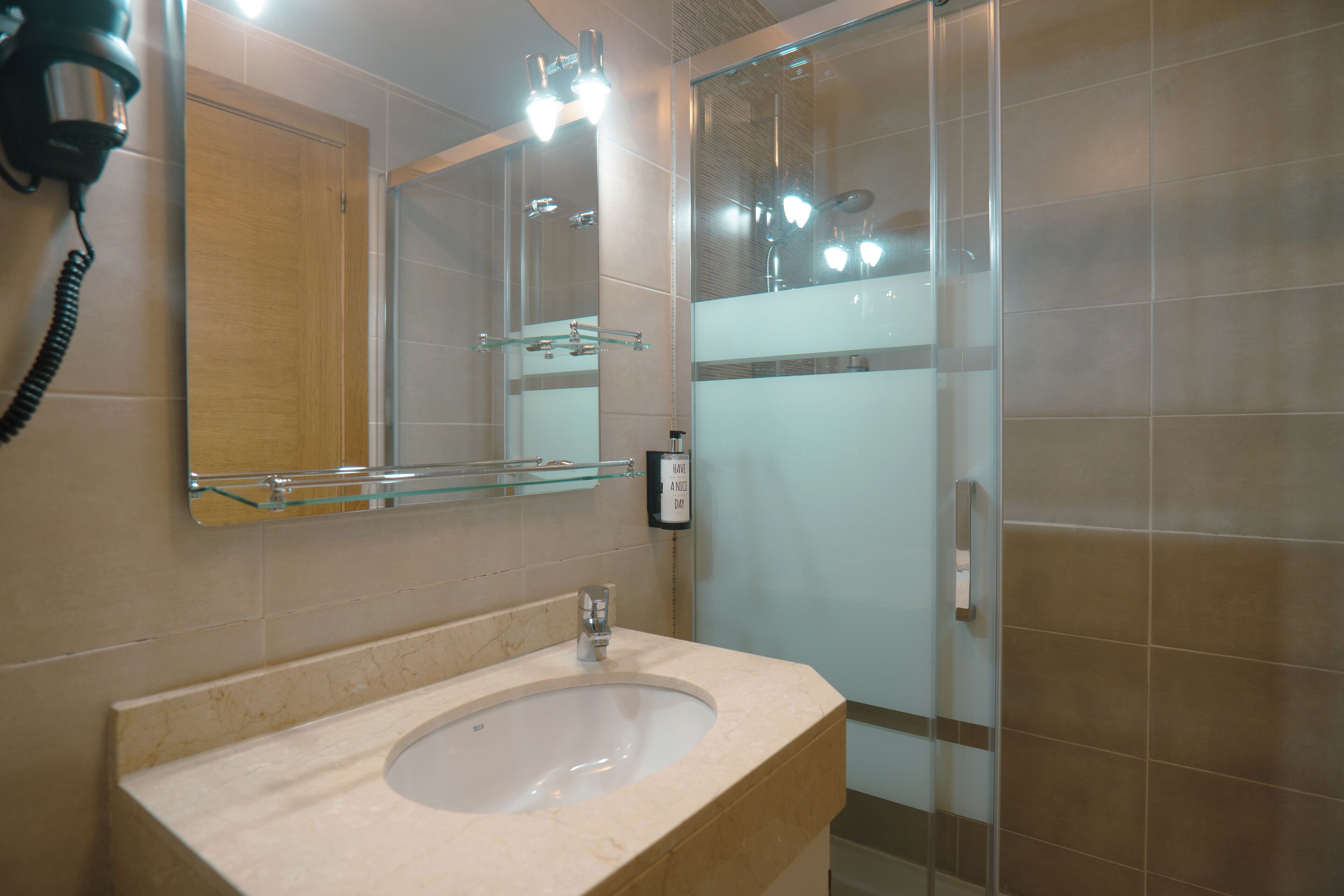 Un baño con lavamanos, espejo y cabina de ducha de vidrio.