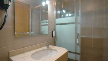 Un baño con lavamanos, espejo y cabina de ducha de vidrio.