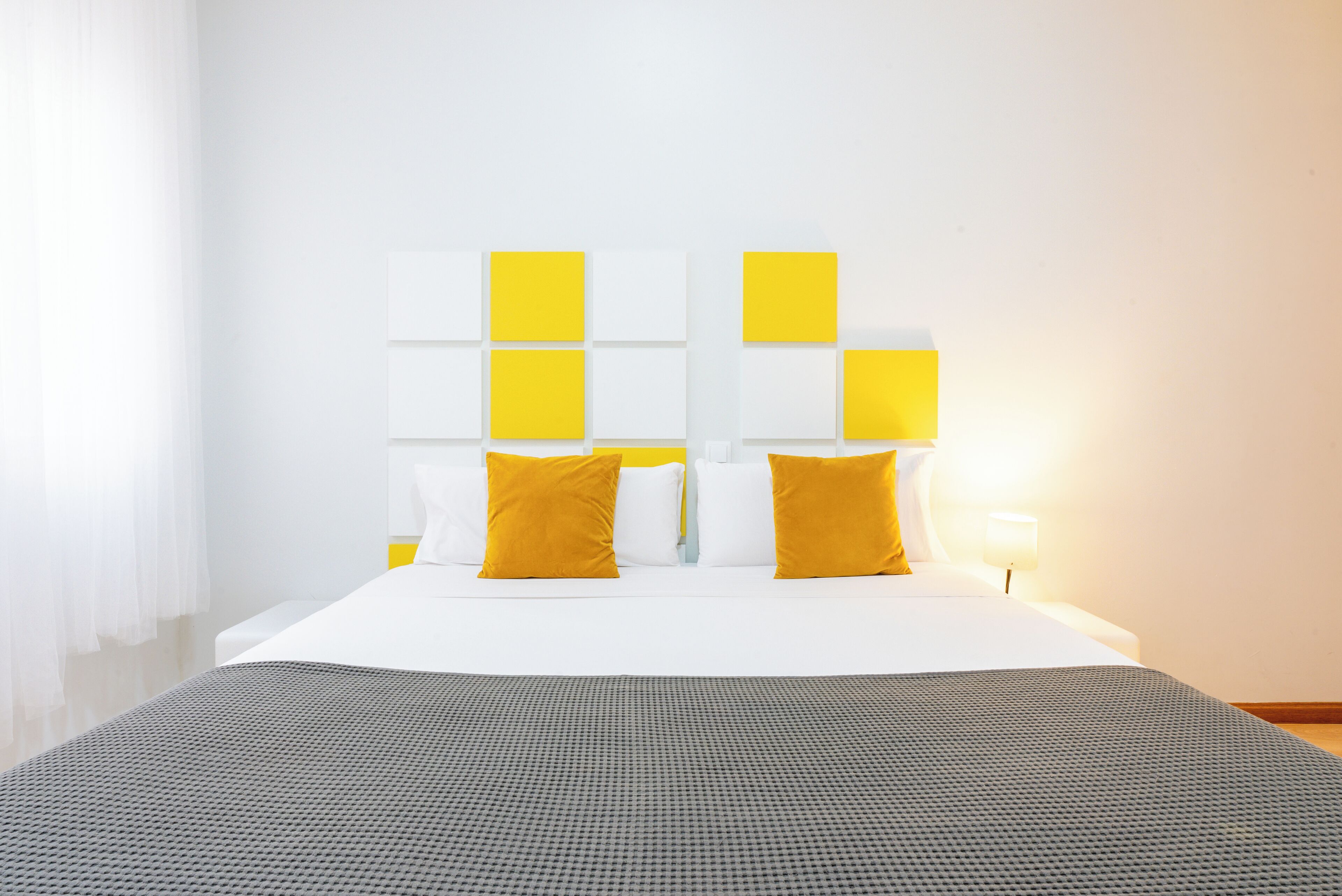A hotel room with a large bed, white bedding, and a gray textured area rug.