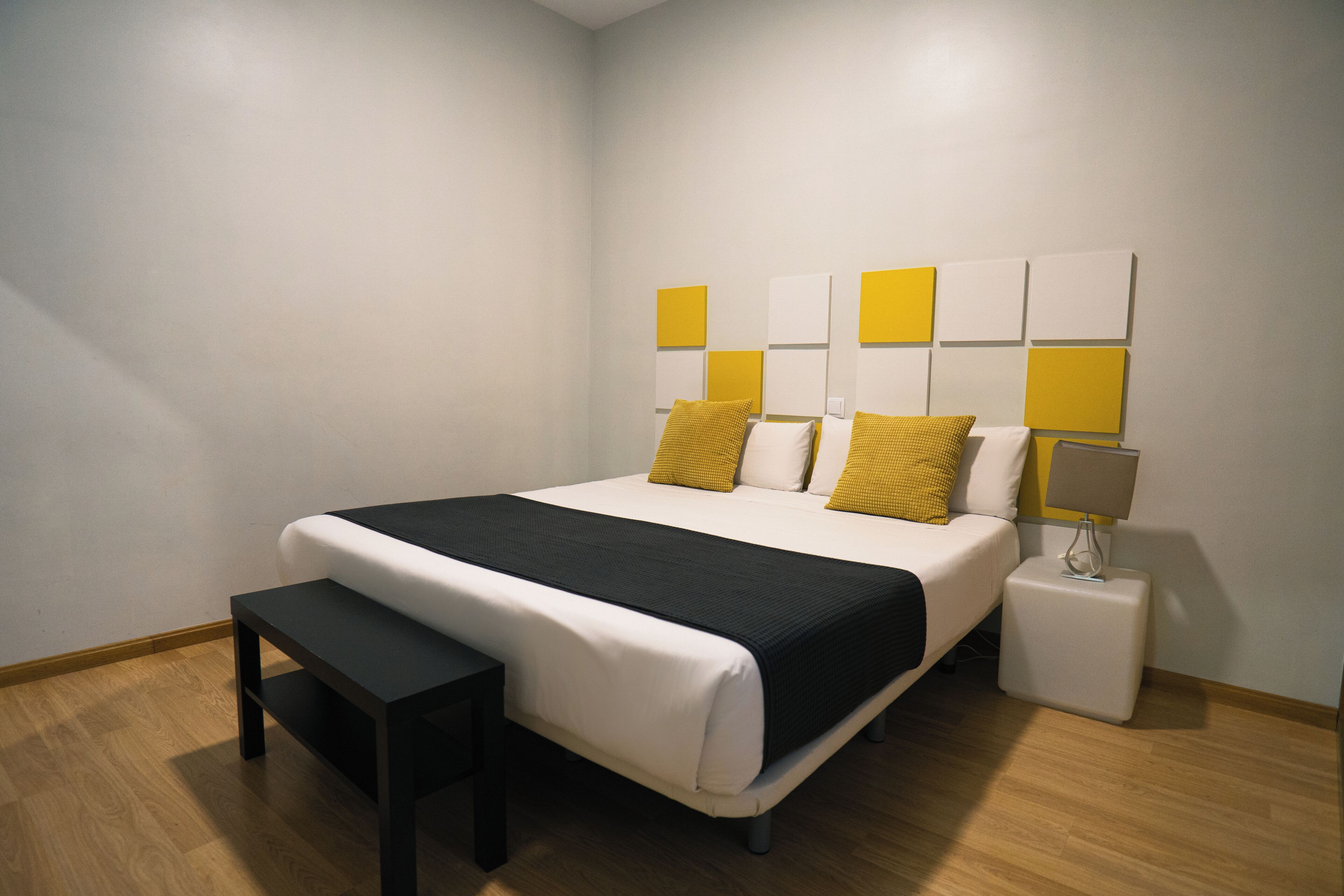 A modern bedroom with a bed, bedside tables, and a bench.