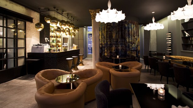 A modern bar area with round tables, bar stools, and a variety of bottles on shelves. - Empreinte Hôtel & Spa (Orléans)