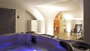 A modern bathroom with a freestanding bathtub, a shower area, and a wooden door leading to a room. - Empreinte Hôtel & Spa (Orléans)