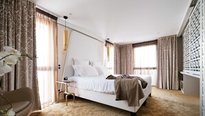 A modern bedroom with a large bed, a bedside table, a chair, and a desk. - Empreinte Hôtel & Spa (Orléans)
