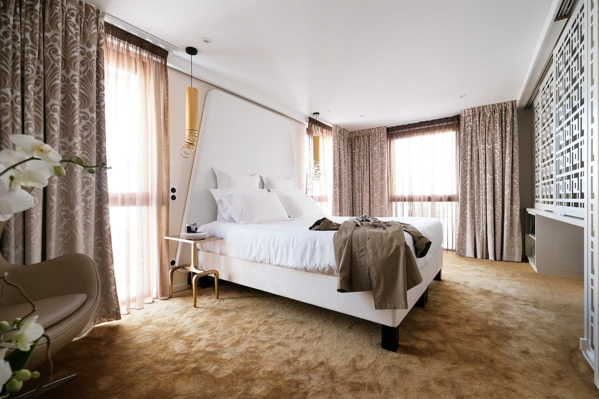 A modern bedroom with a large bed, a bedside table, a chair, and a desk.