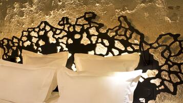 A bed with white linens and a unique black, abstract wall art piece behind it.