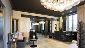 A modern reception area with a reception desk, seating arrangements, and a decorative tree sculpture. - Empreinte Hôtel & Spa (Orléans)