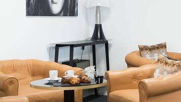 Et værelse med to lædersofaer, et rundt bord med croissanter, en lampe og en radio.