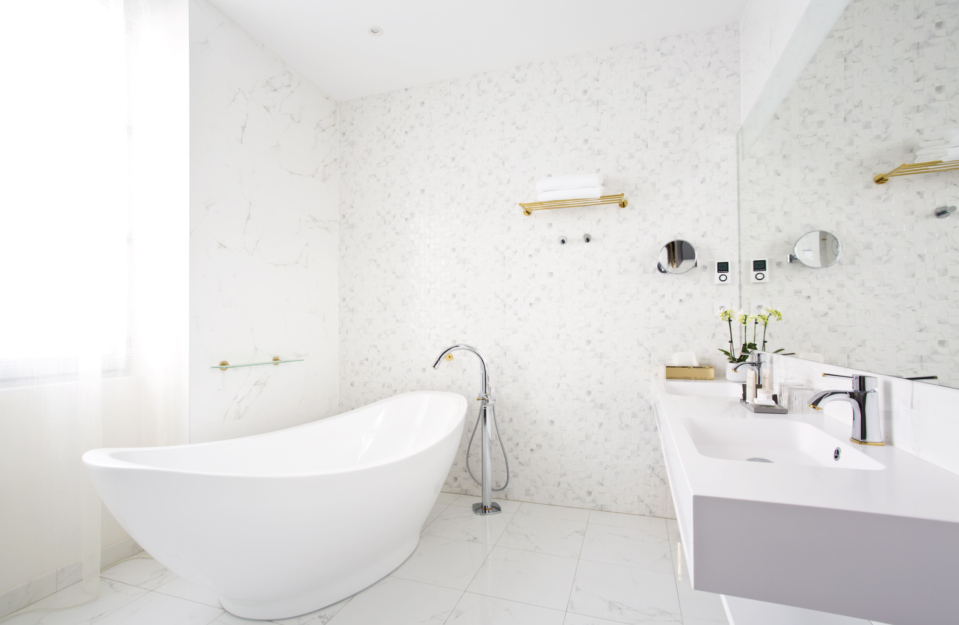 Een moderne badkamer met een vrijstaand bad, een wastafel met spiegel en een douchehoek.