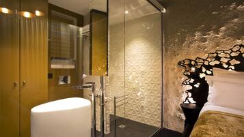 Un baño moderno con cabina de ducha de vidrio, un lavabo blanco y una pared con textura.