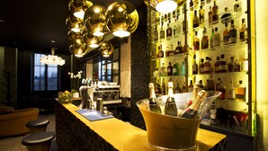 A bar area with a champagne bucket, bar stools, and a well-stocked liquor shelf. - Empreinte Hôtel & Spa (Orléans)