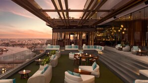 A rooftop lounge with outdoor seating, a view of the city, and a glass railing. - Avani+ Riverside Bangkok Hotel (Bangkok)
