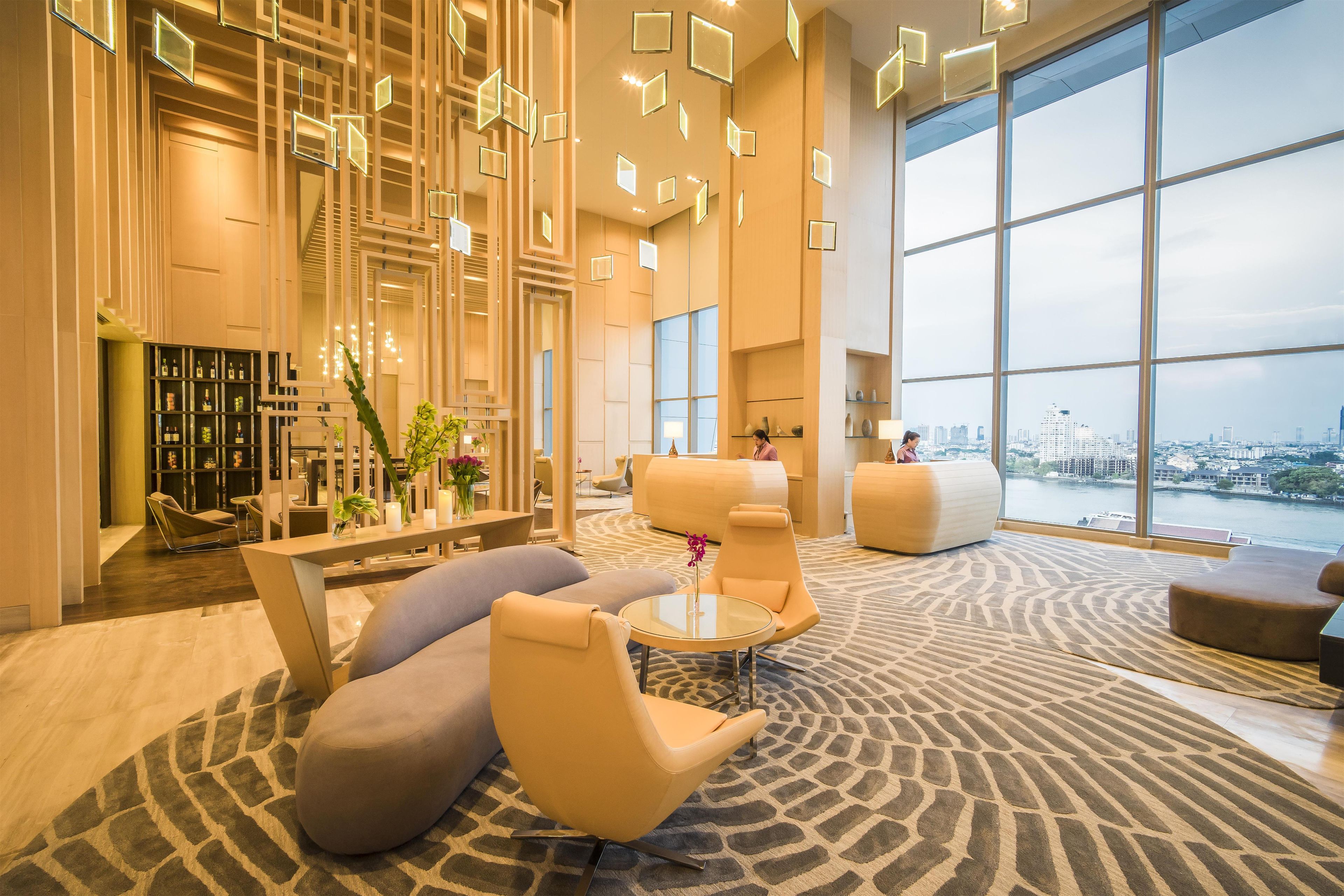 A spacious lobby with modern furniture, a large window offering a city view, and a reception desk.
