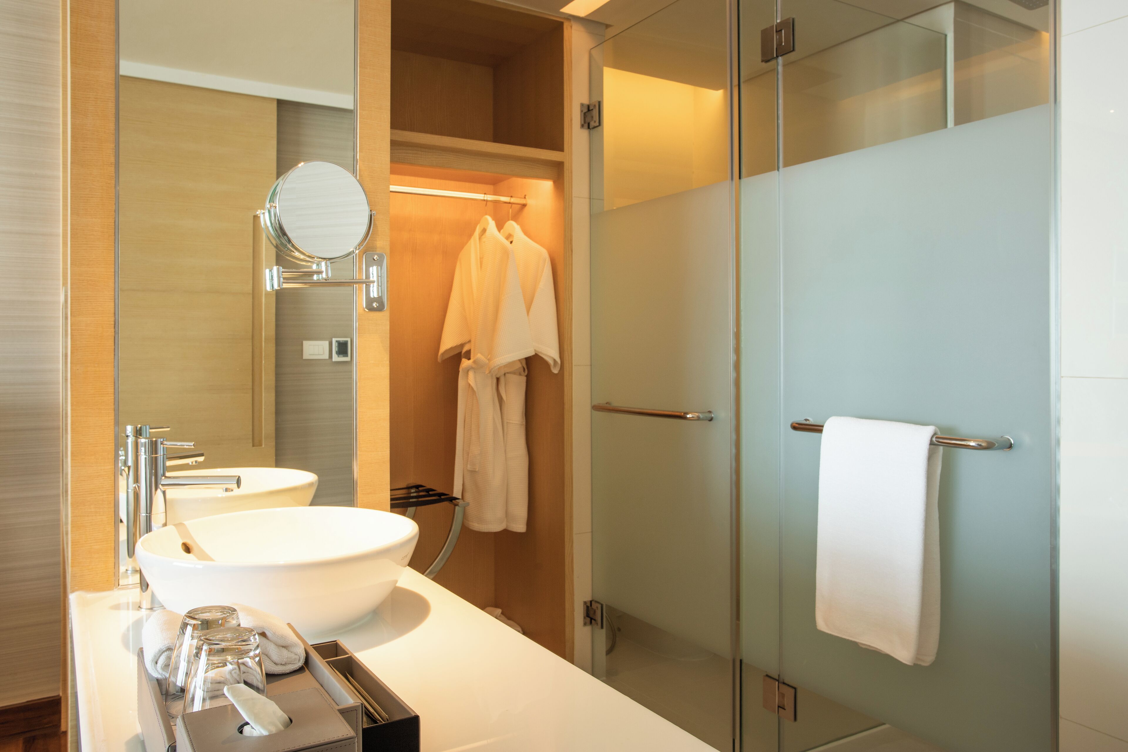 A modern bathroom with a large white sink, a mirror, and a glass shower enclosure.