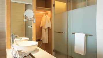 A modern bathroom with a large white sink, a mirror, and a glass shower enclosure.