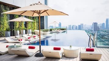 Una piscina al aire libre, sombrillas, sillones reclinables de piscina