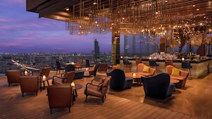 A rooftop bar with leather seating and a city view at dusk. - Avani+ Riverside Bangkok Hotel (Bangkok)