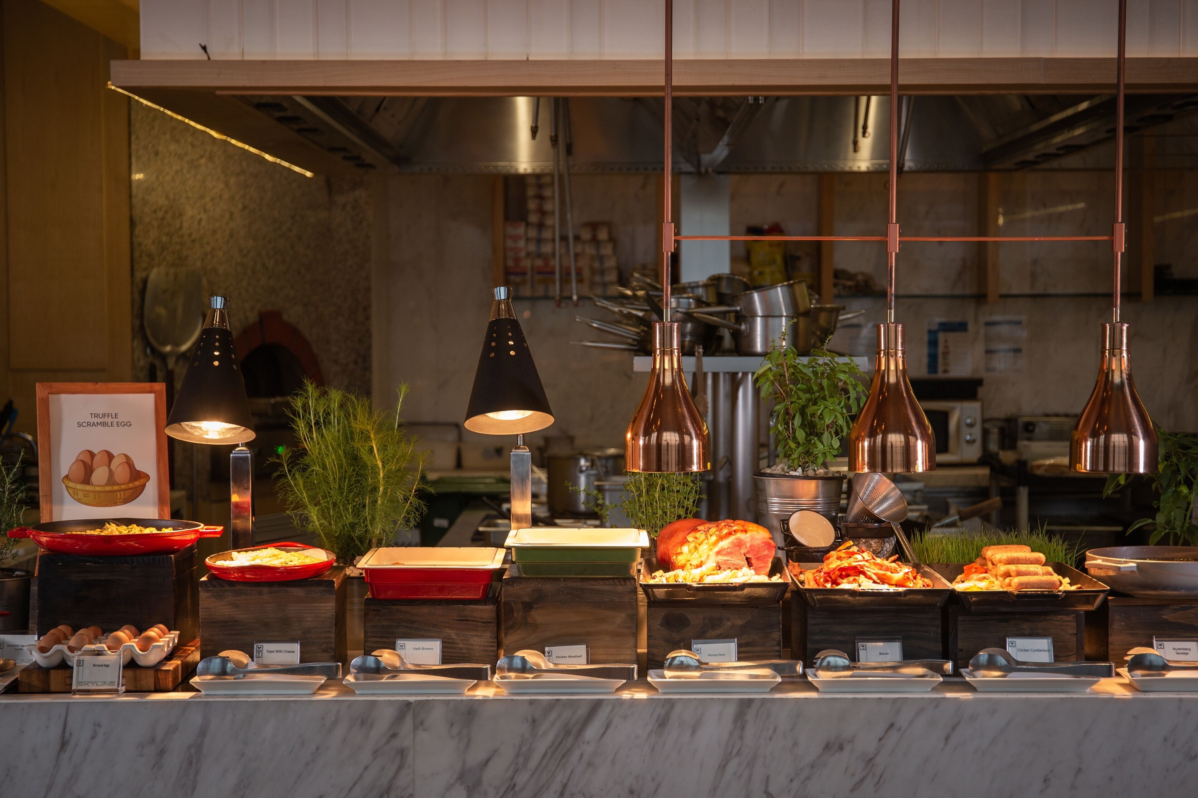 A buffet with various food items and a kitchen in the background.