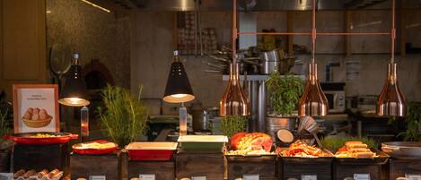 A buffet with various food items and a kitchen in the background.
