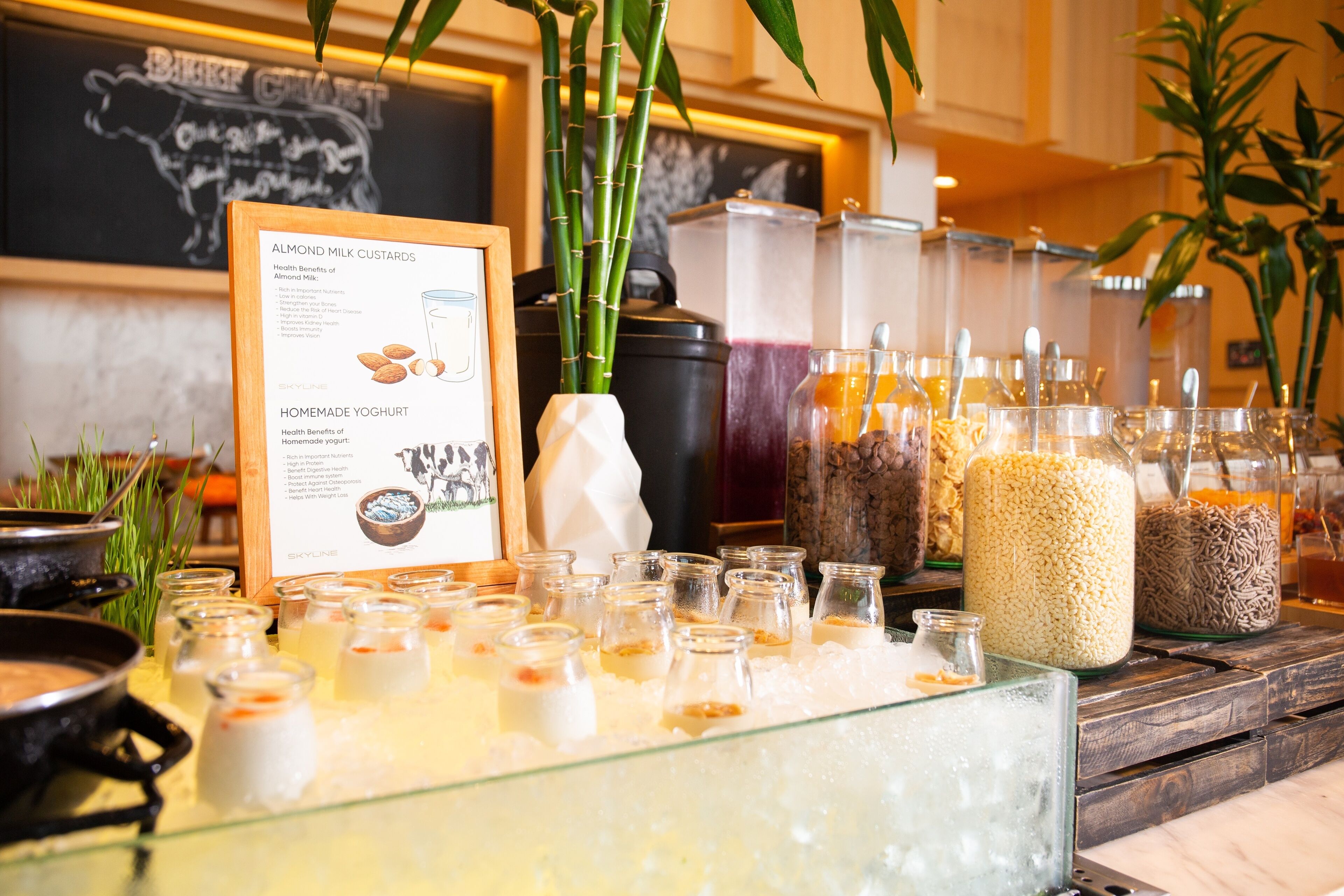 A buffet with various food items and a sign detailing the health benefits of almond milk and homemade yogurt.