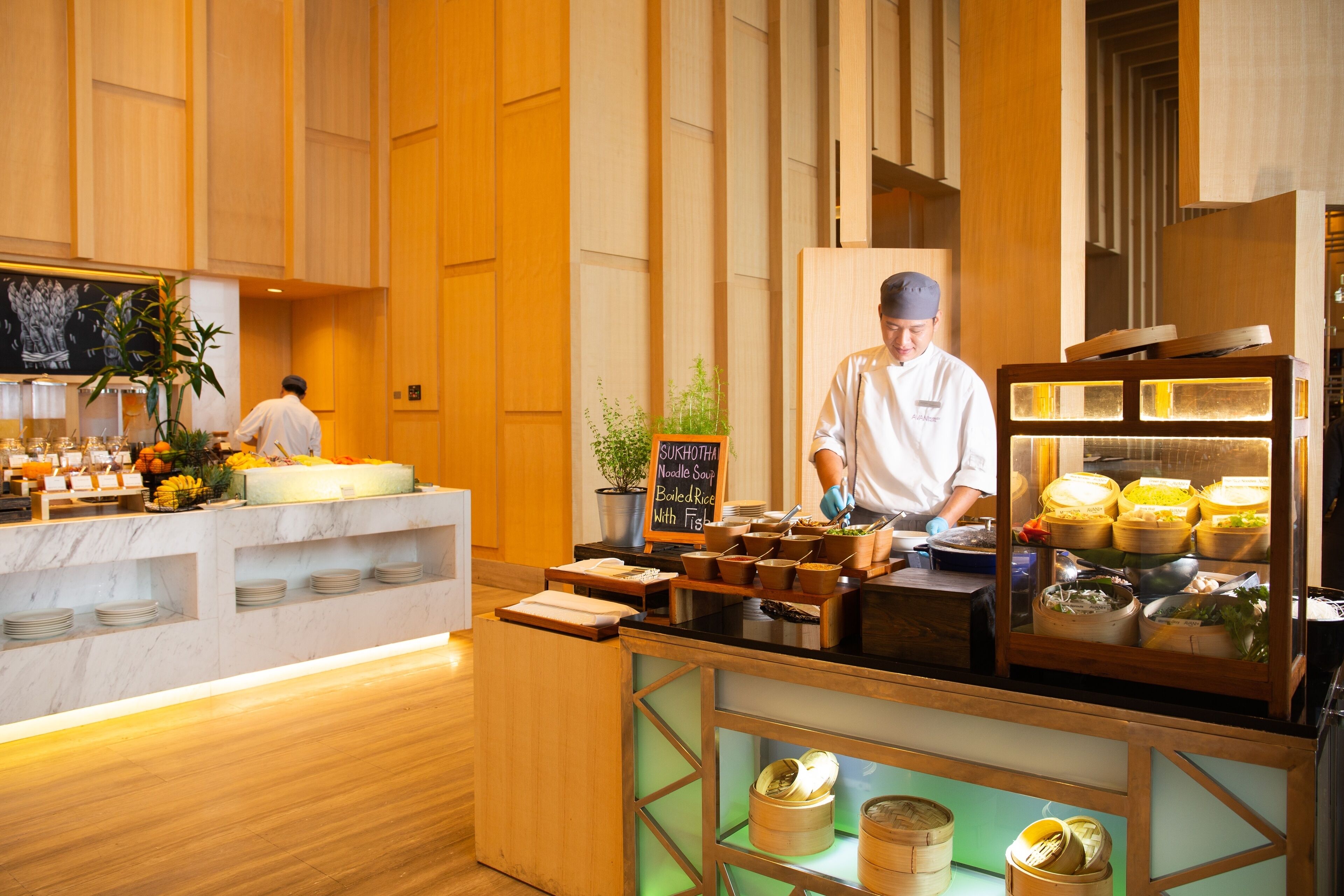 A buffet counter with various food items and a chef preparing food.