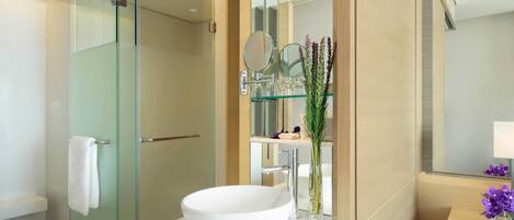 A modern bathroom with a glass-enclosed shower, a white sink, and a mirror with two round mirrors.